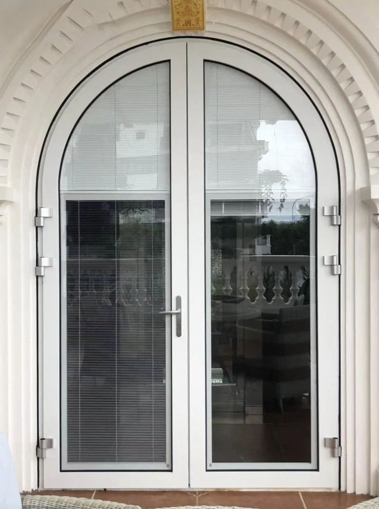 Arched glass door with blinds inside, surrounded by decorative white trim and a small yellow plaque above.