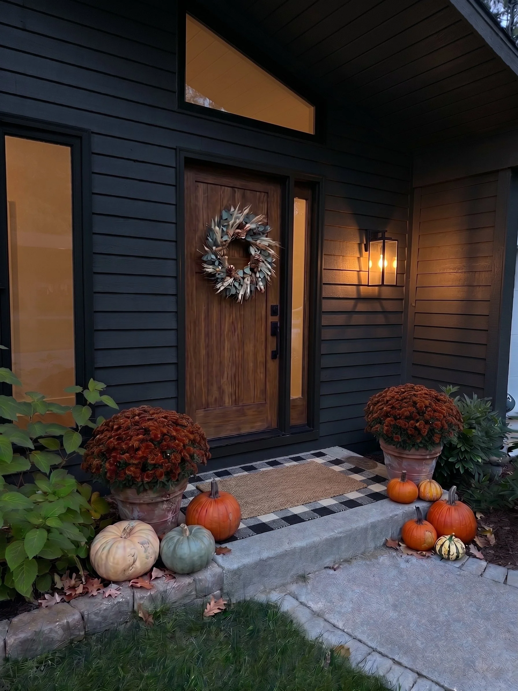 The Welcome Home autumn porch display - burgundy mums, heirloom pumpkins and gourds at a front door
