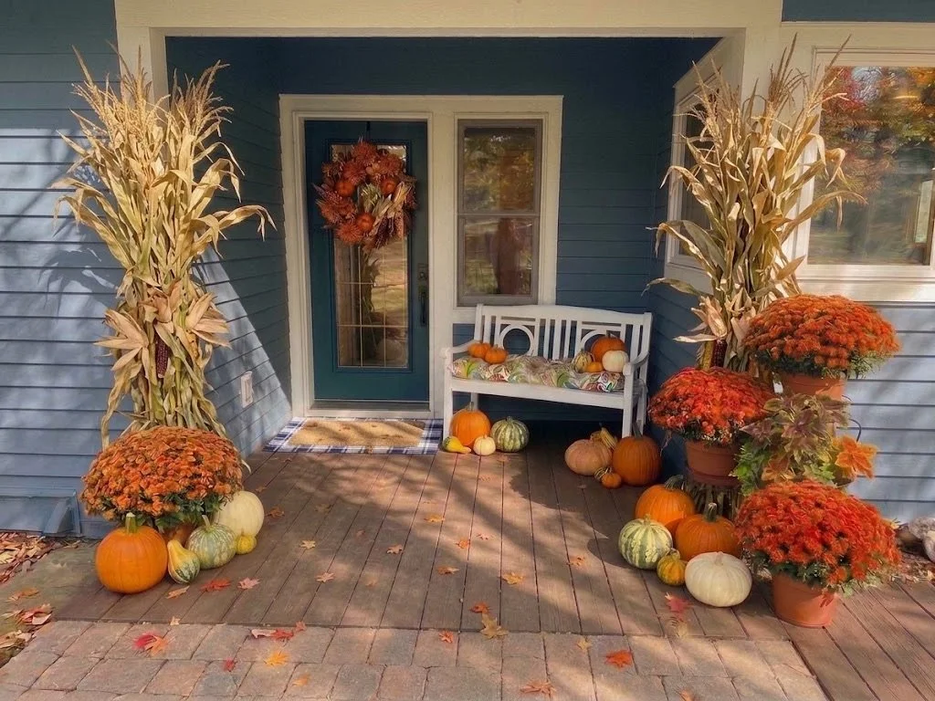 The Designer Doorstep autumn display - mums, cornstalk bundles, a wreath and heirloom pumpkins at a front door