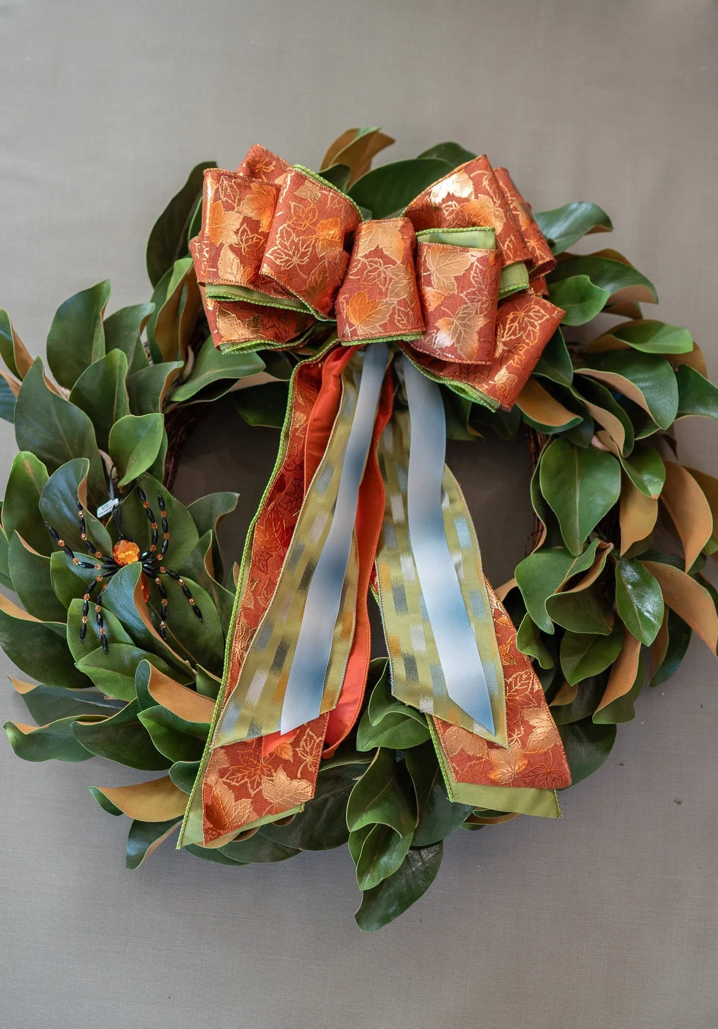 A green wreath decorated with an orange and gold bow.