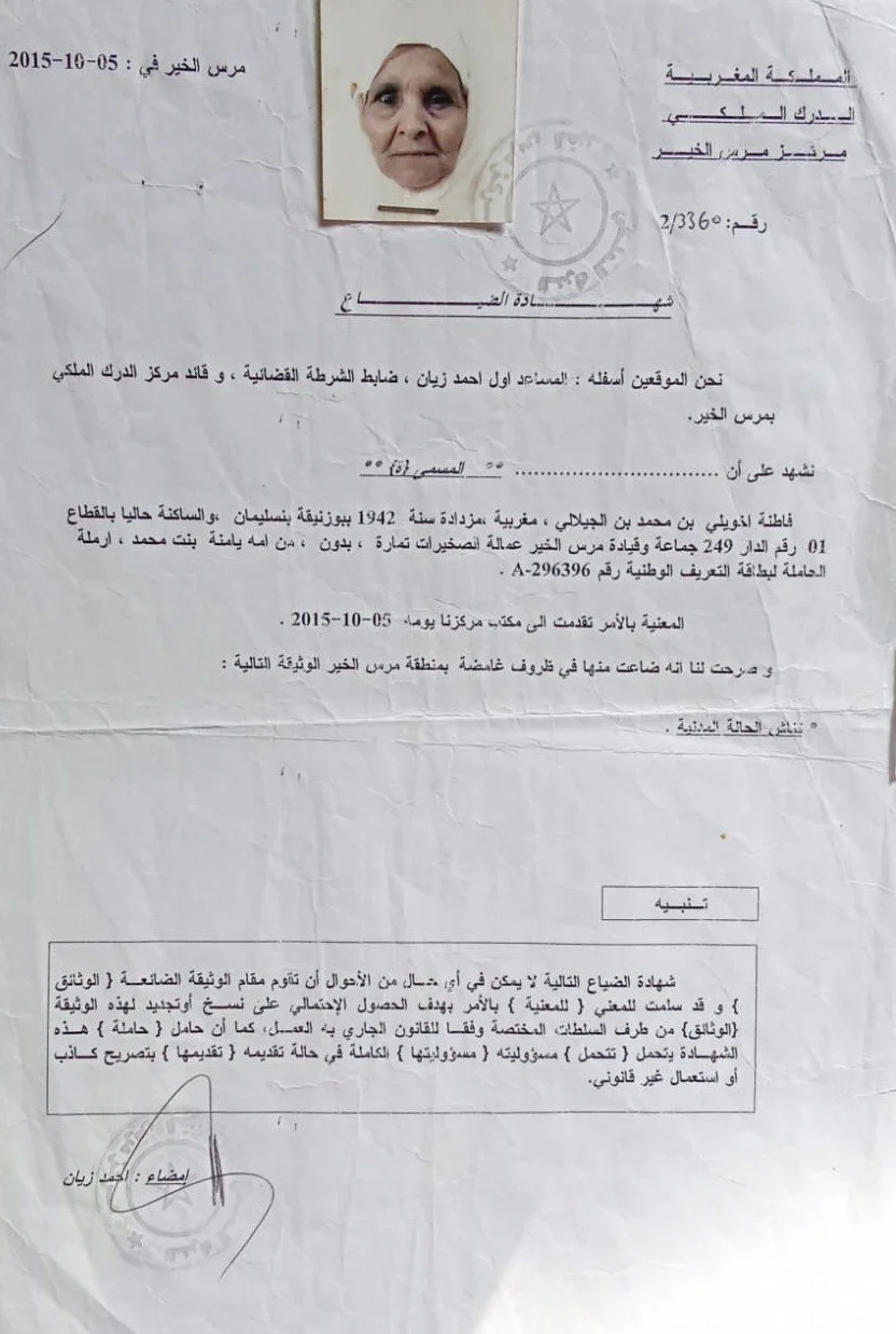 A document in Arabic with a photograph of an elderly woman at the top, including official stamps and signatures. The document appears to be an official letter or certificate issued by the Moroccan government.