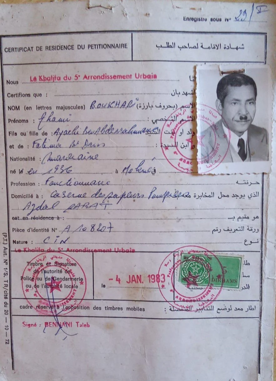 A document titled 'Certificat de Residence du Petitionnaire' with handwritten details in French and Arabic, a photograph of a man in a suit, red official stamps, and a green sticker, dated January 4, 1983.