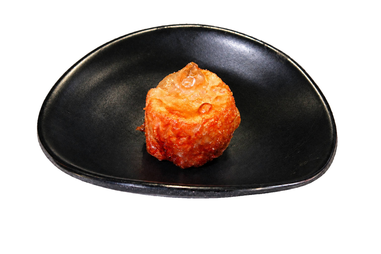 A roasted and glazed piece of chicken served on a black plate.