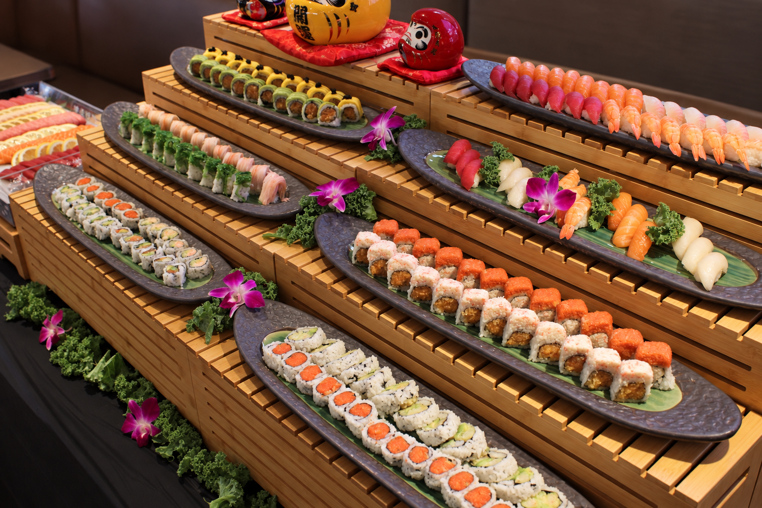 Assorted sushi rolls displayed on black and green platters decorated with purple flowers and greenery, set on a layered wooden stand.