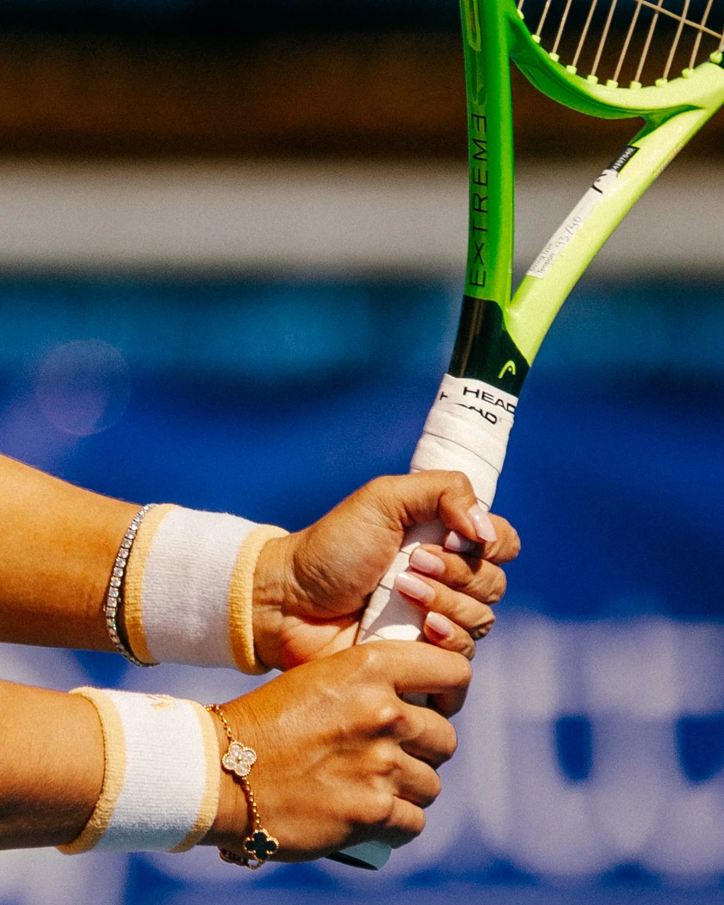 Beau Chevalier photo of Close-up of a person holding a green tennis racket inside a tennis court. The person's hand shows jewelry, including a bracelet and a ring.