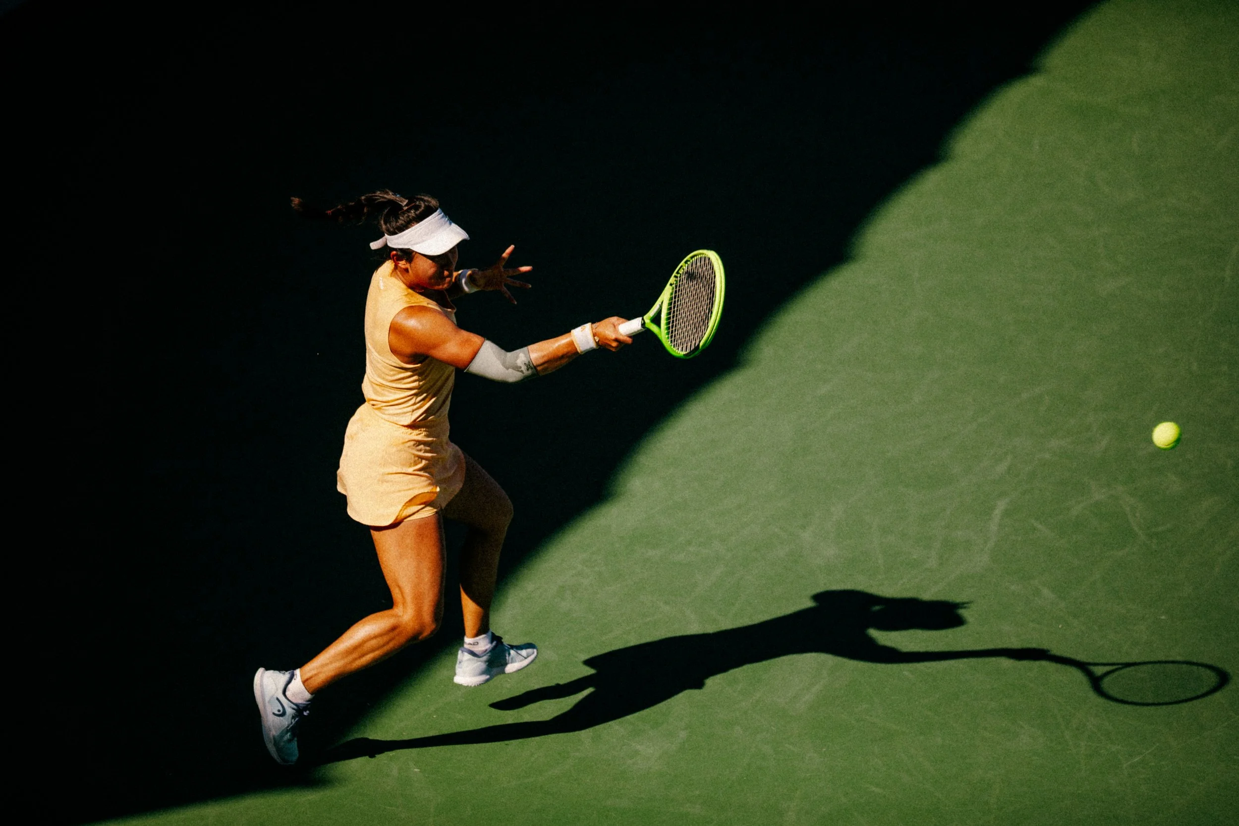 A female tennis player hitting a tennis ball with a racket on a tennis court during daytime.