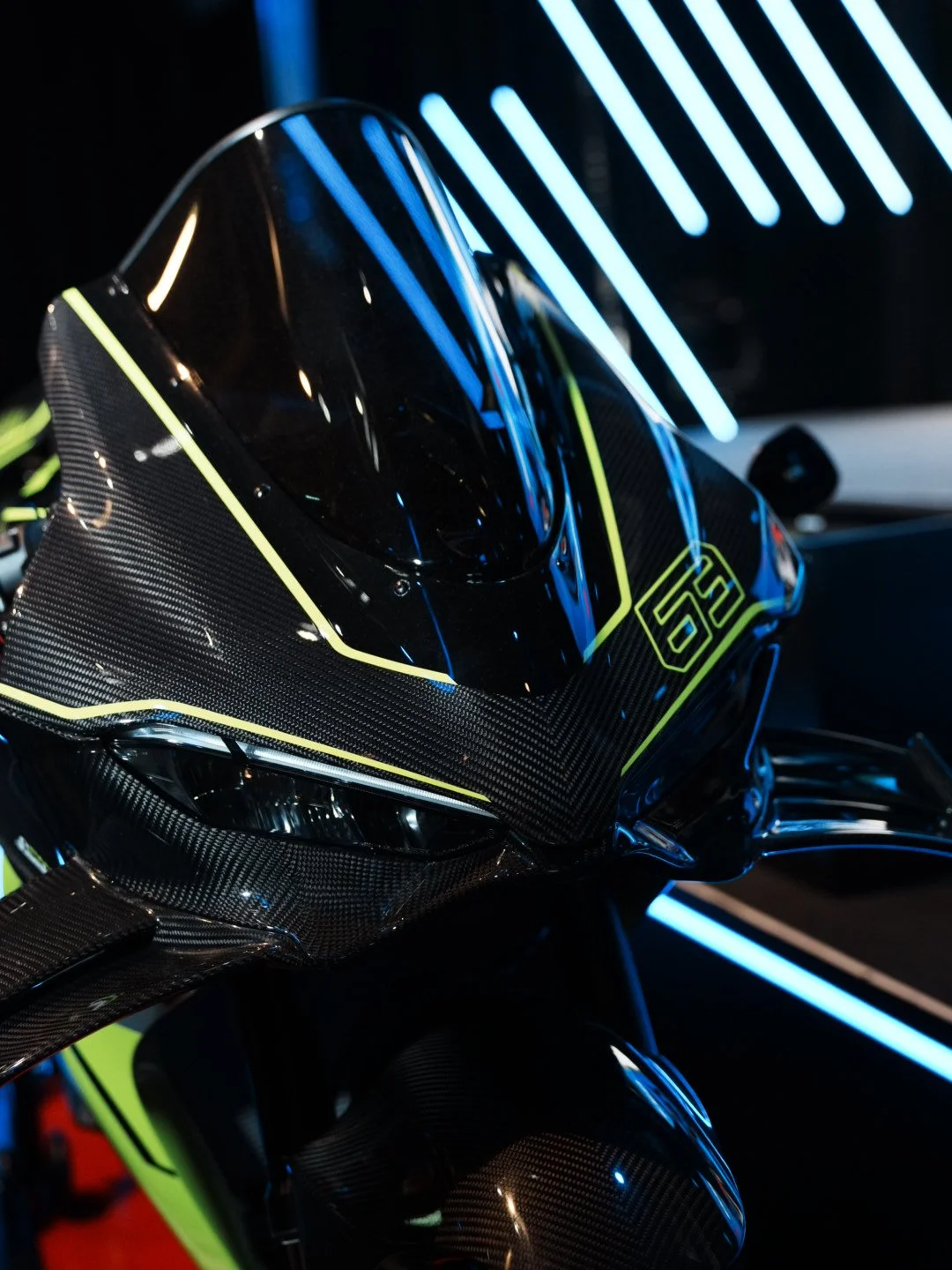 Close-up of a futuristic motorcycle with black and neon green accents, illuminated by blue LED lights.