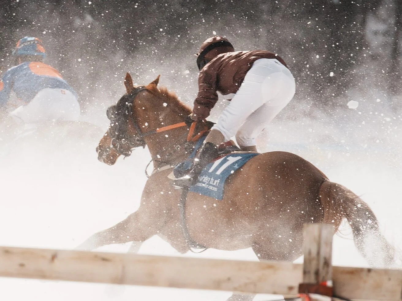 A horse race in snowy weather, with jockeys riding horses through falling snow.
