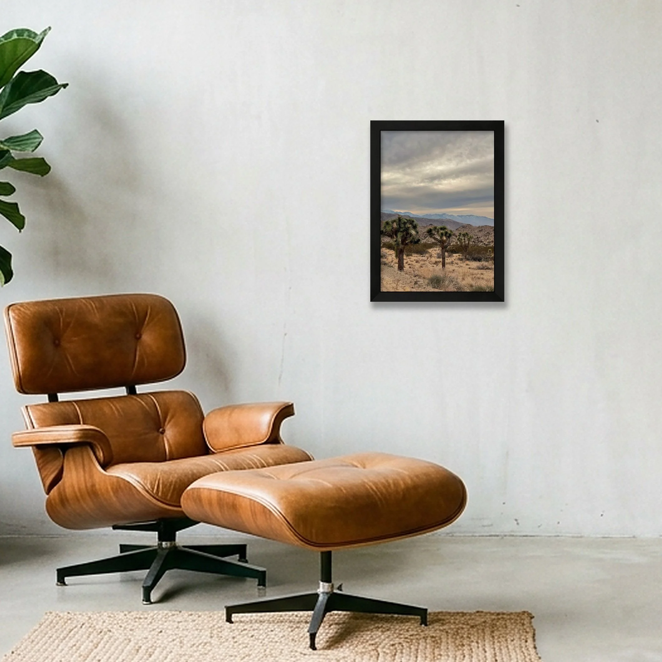 A black wooden gallery frame displaying a fine art print of dark storm clouds hovering over a high desert mountain landscape with a wide cream mat border.
