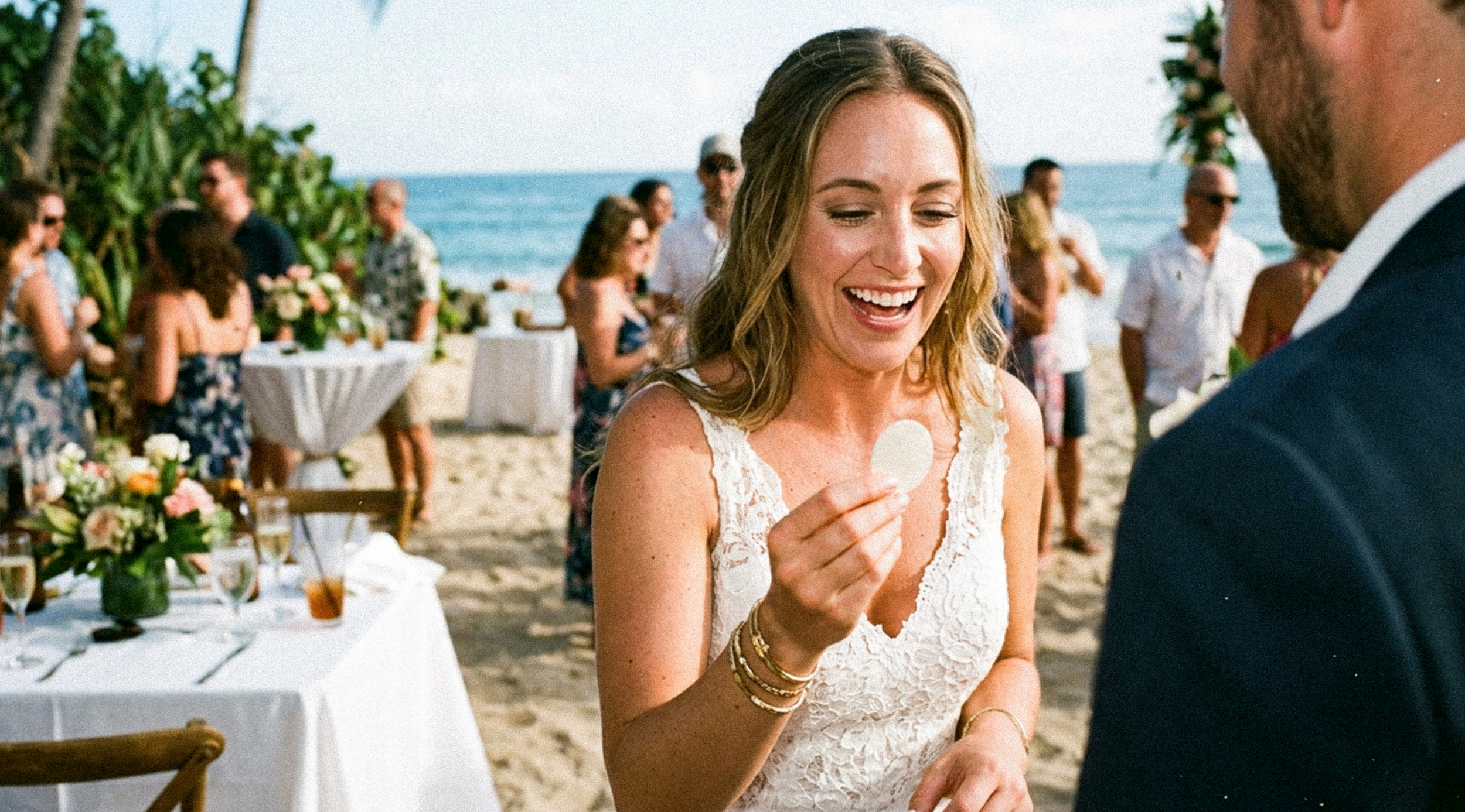 A smiling bride holding a custom sticker favor at a beach wedding reception.