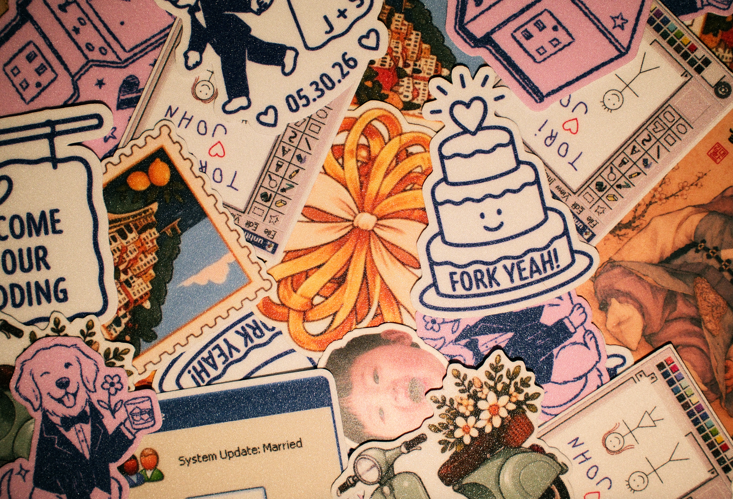 A collection of colorful stickers on a surface, including illustrations of buildings, hearts, a birthday cake, a dog, a gaming controller, and various text messages.