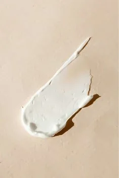 smear of white cream on beige background