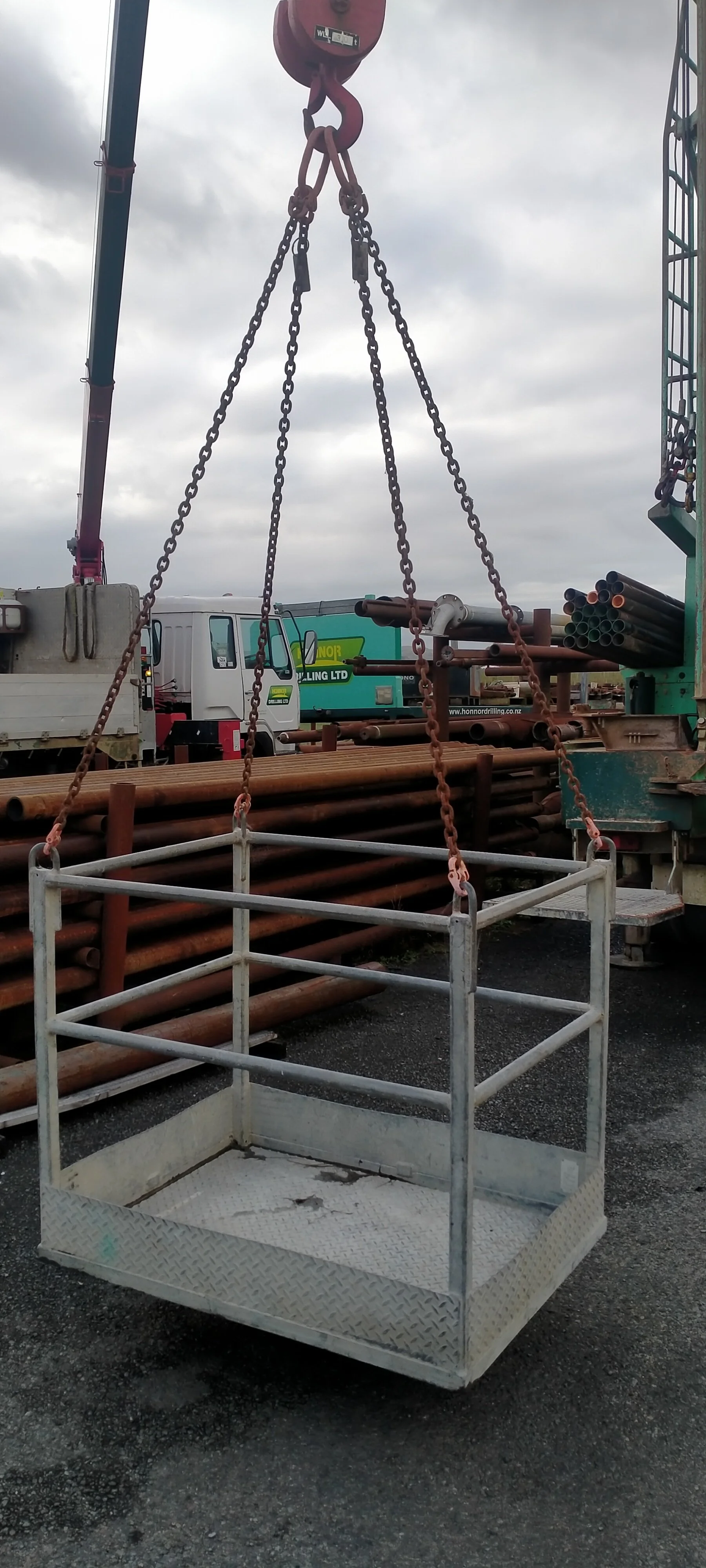 A construction site with a man cage lift basket.