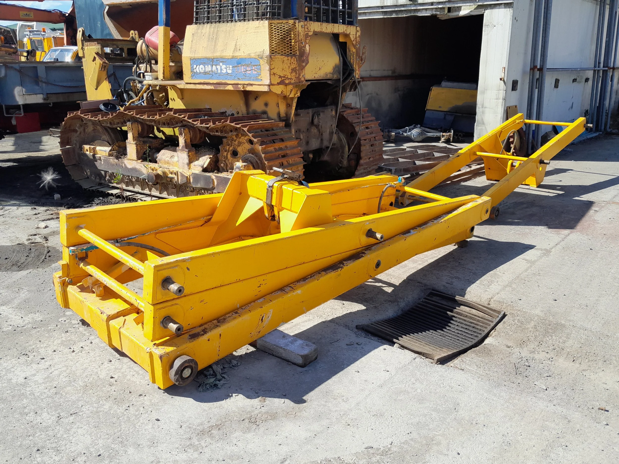 A partially assembled, EWP frame with tracks, hydraulic cables, and structural components, in a workshop or garage setting.