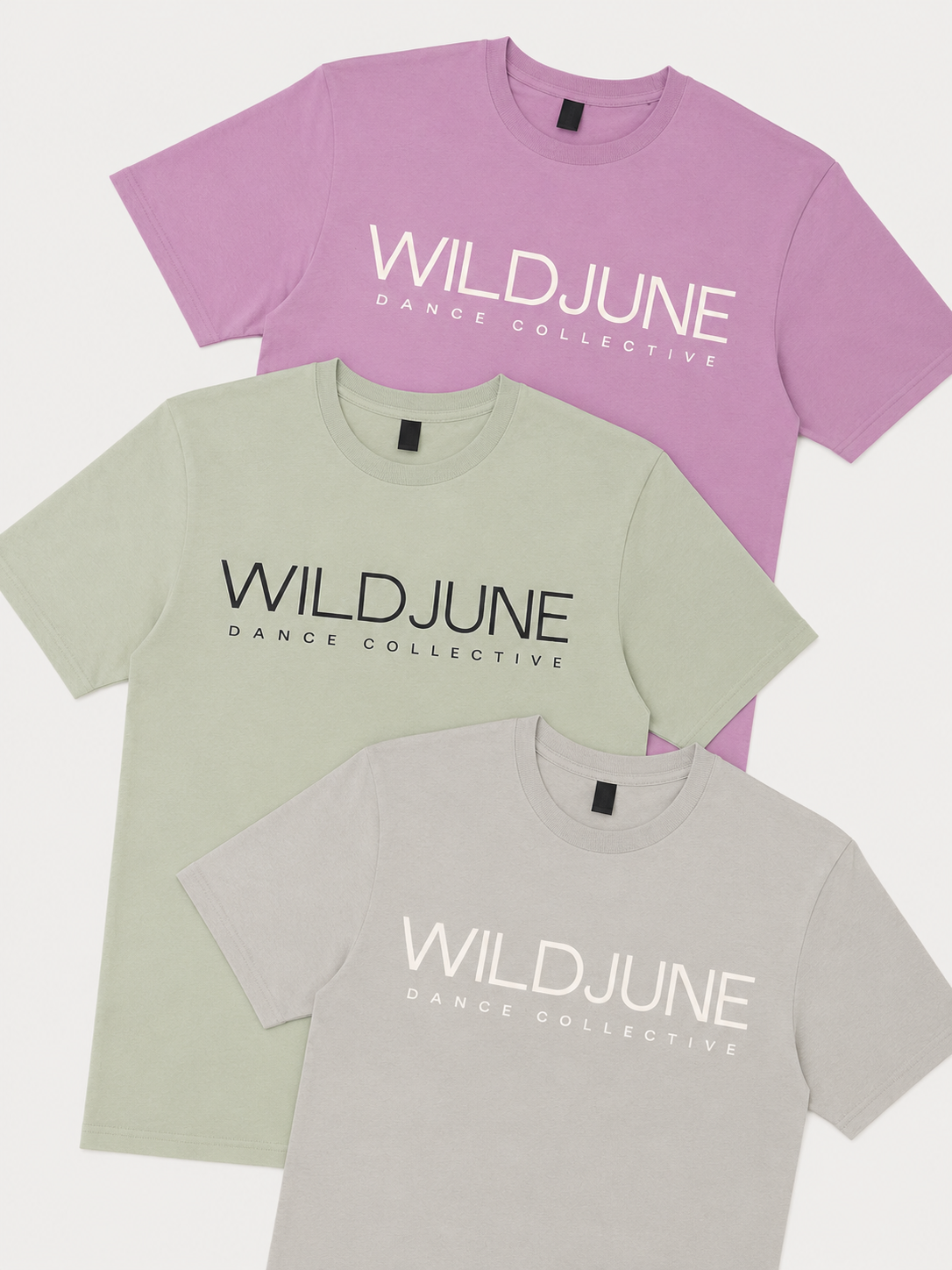 Three pastel-colored T-shirts in purple, green, and gray, each with the text 'WILDJUNE DANCE COLLECTIVE' printed on the front, layered on top of each other against a white background.