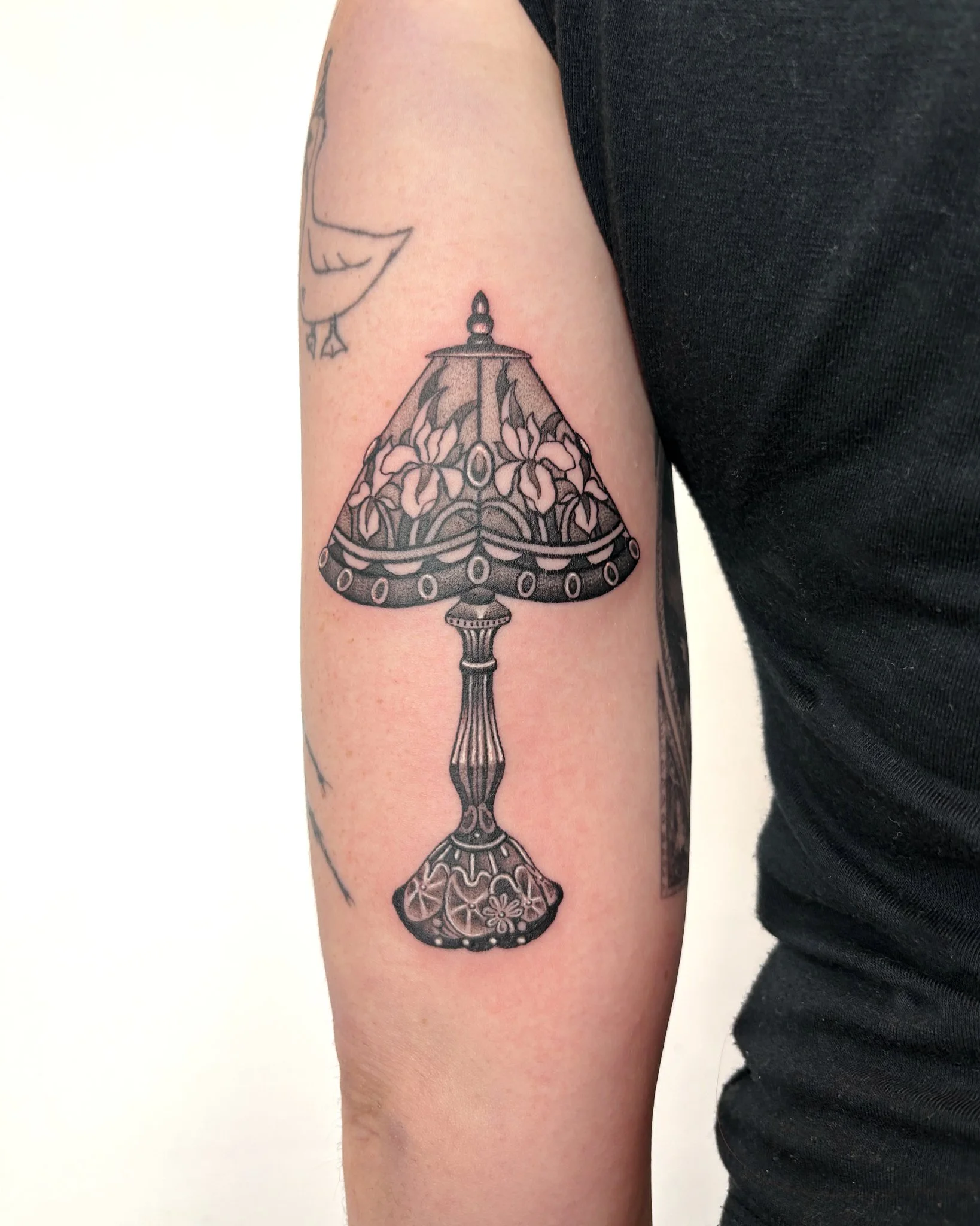 Tattoo of a decorative lamp on a person's upper arm.