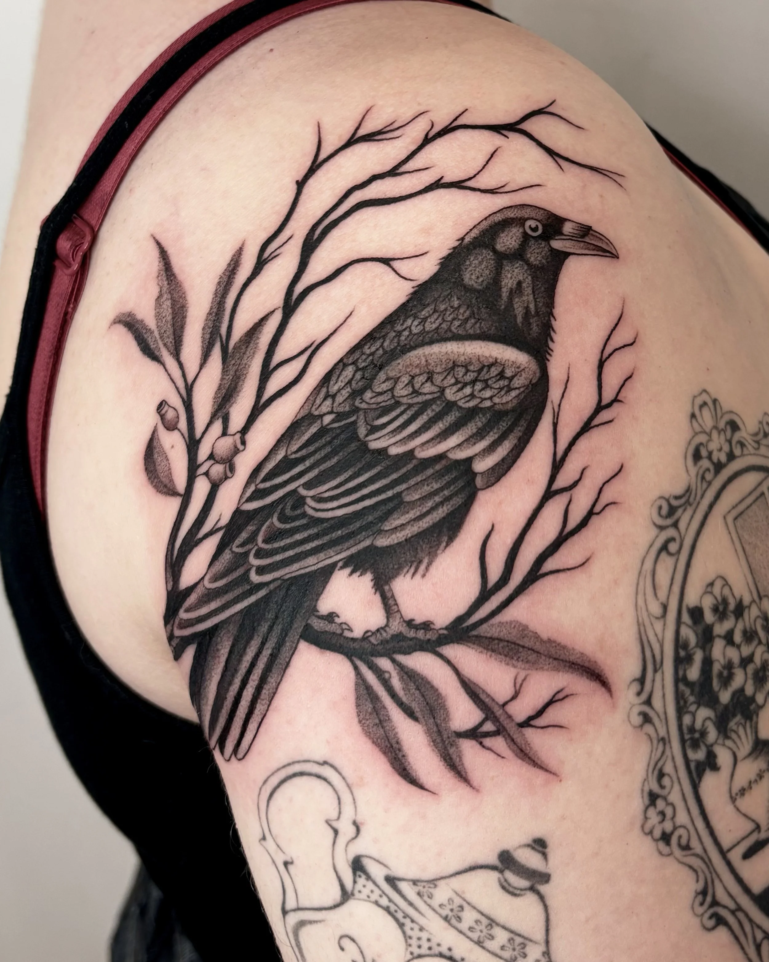 Tattoo of a bird with a branch and leaves on a person's arm.