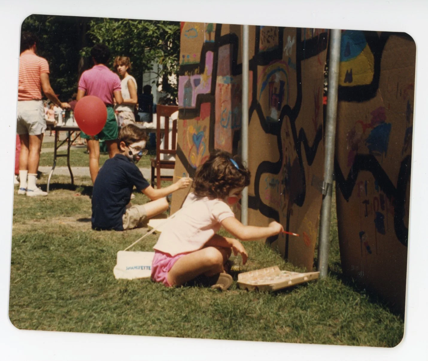 Children painting large panels at an outdoor event.