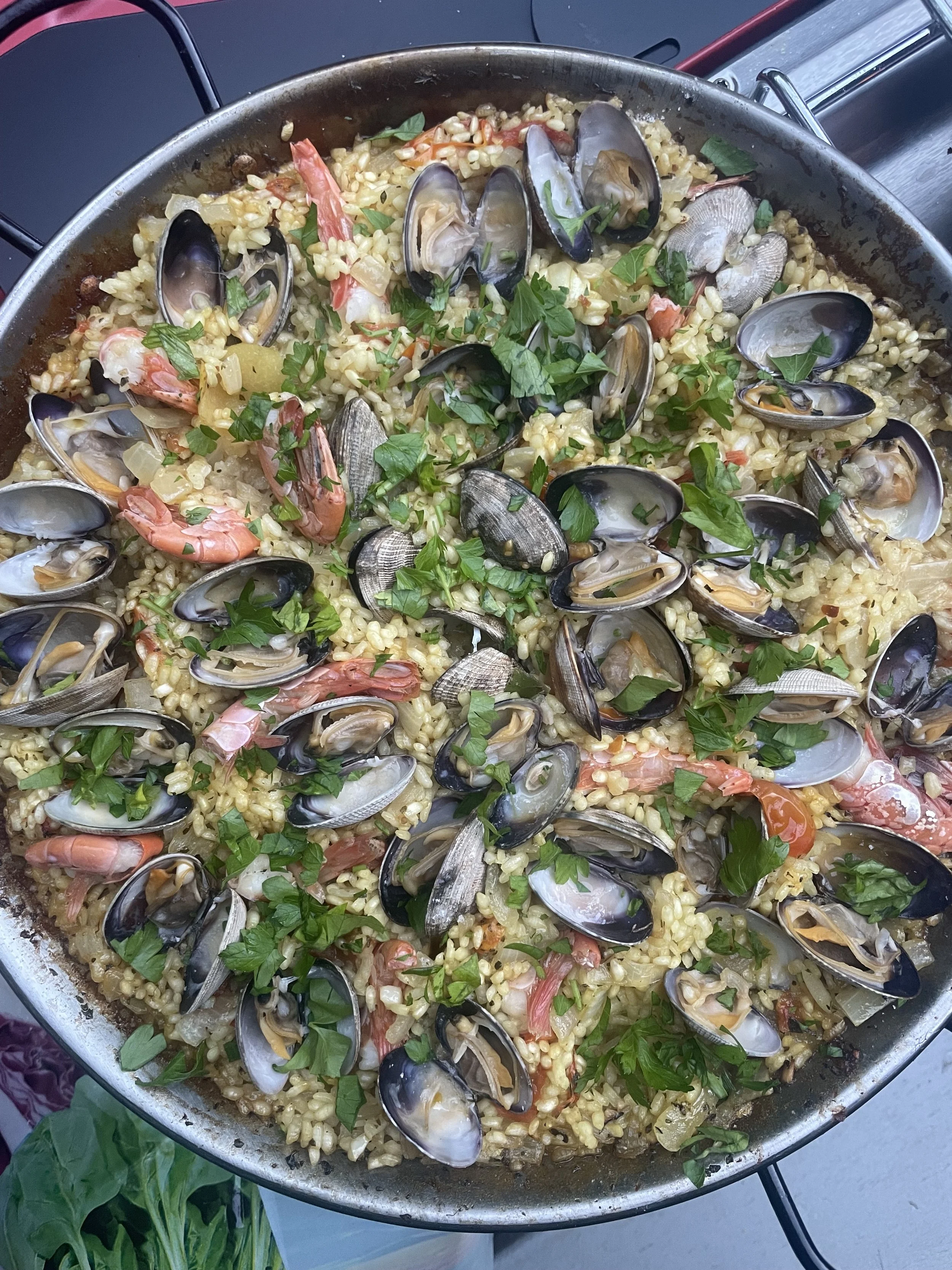 Seafood paella with mussels, shrimp, and chopped parsley garnished on top.