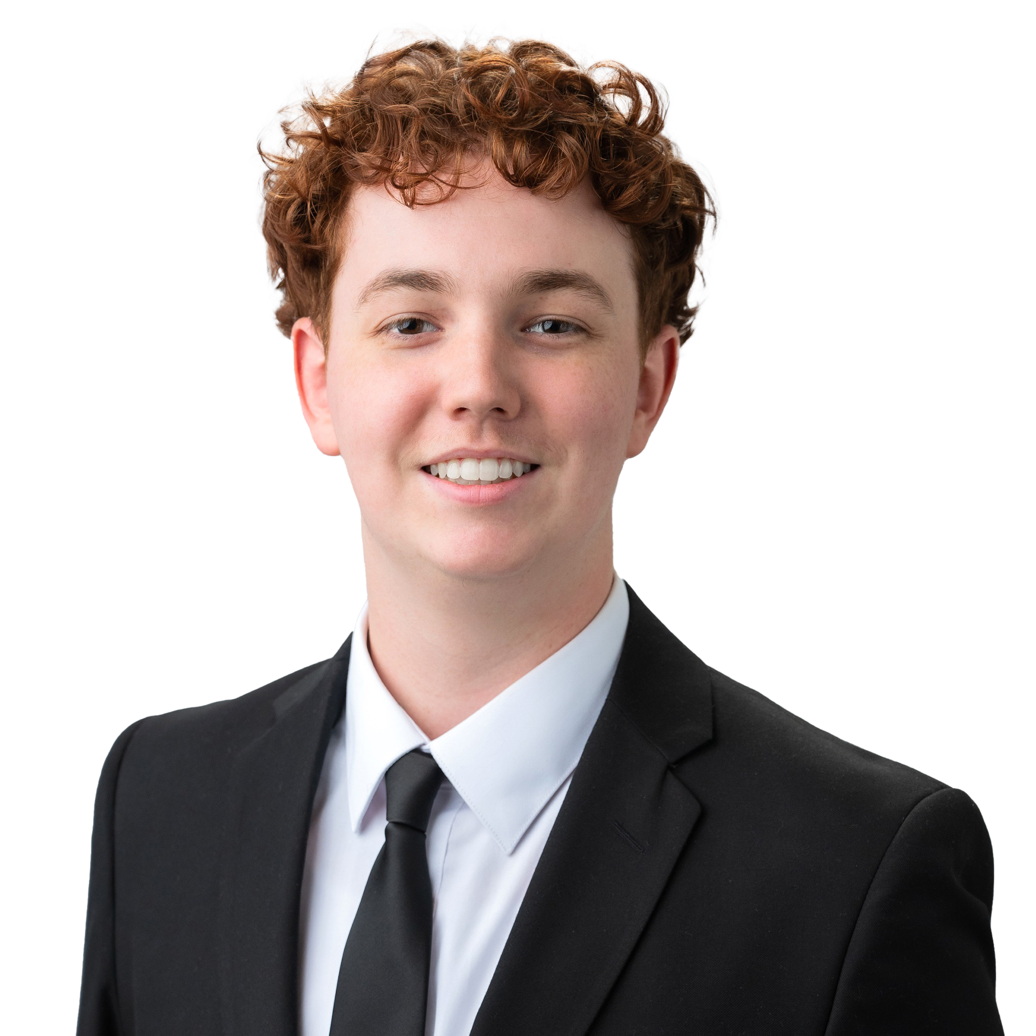 Close-up of a young man with curly red hair, wearing a black suit, white shirt, and black tie, smiling against a white background.