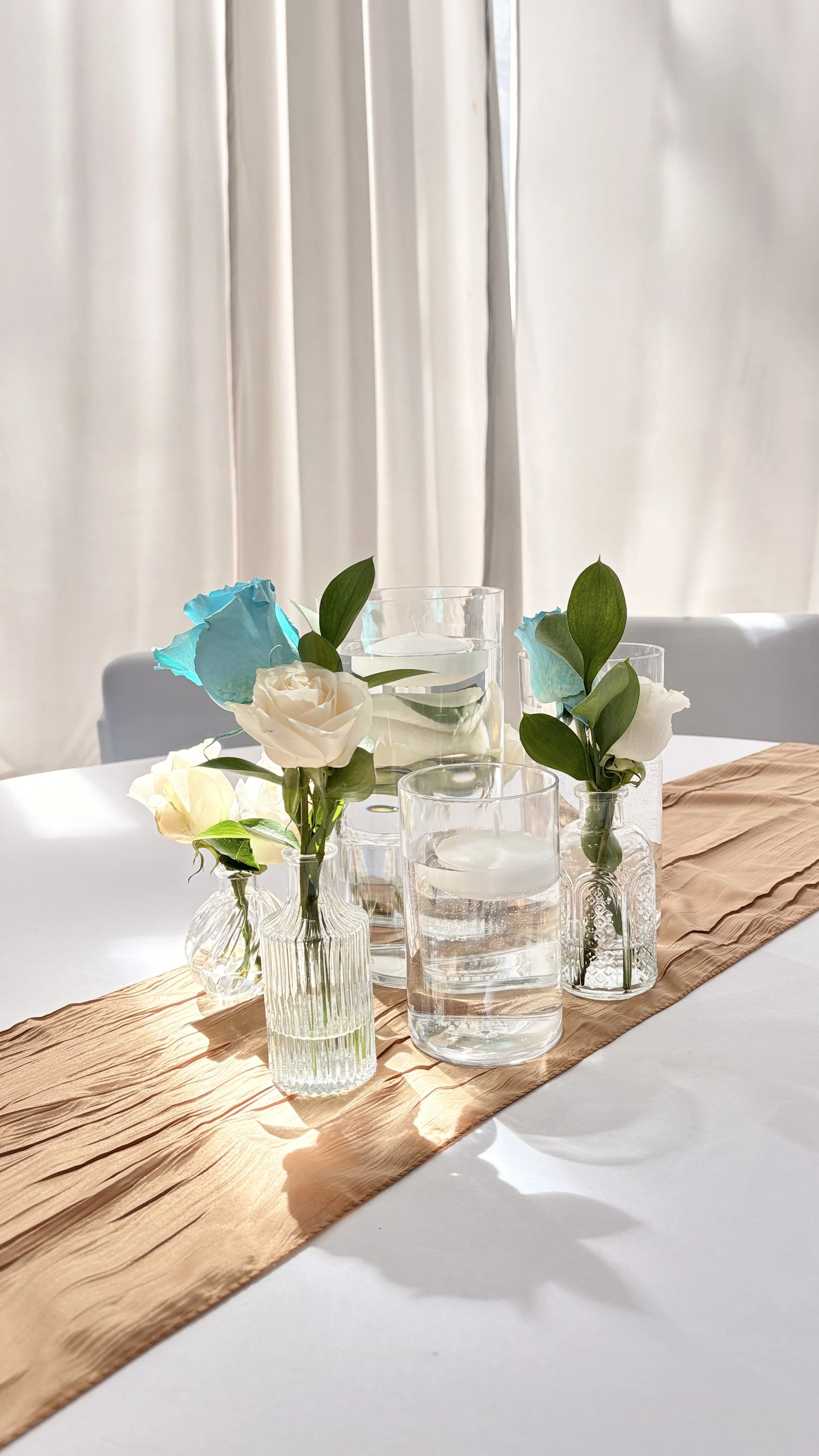 A tabletop centerpiece with florals bud vases and floating candles