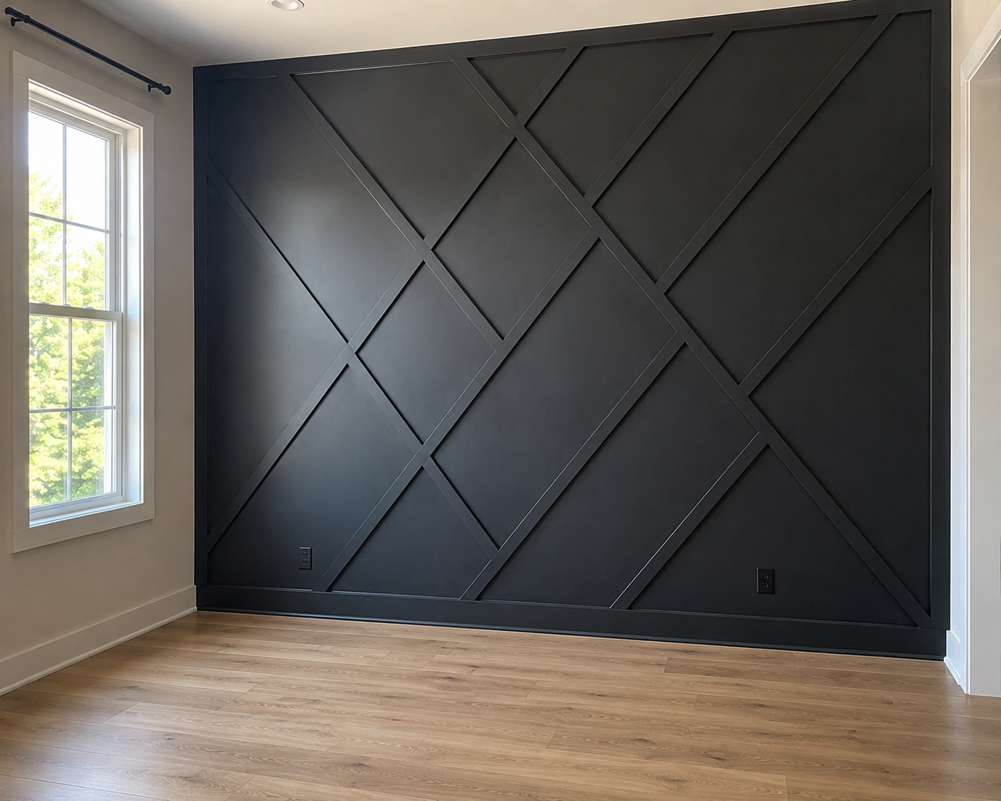 Empty room with a dark accent wall featuring geometric paneling, light wooden flooring, and a window with white trim bringing in natural light.