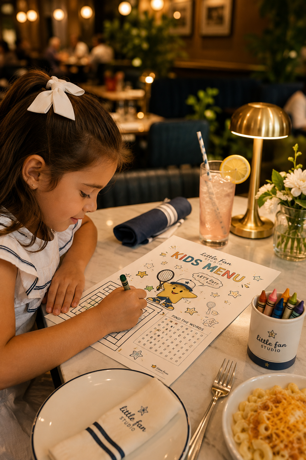 Young girl coloring a custom kids' menu at a restaurant table with crayons, food, and a drink.