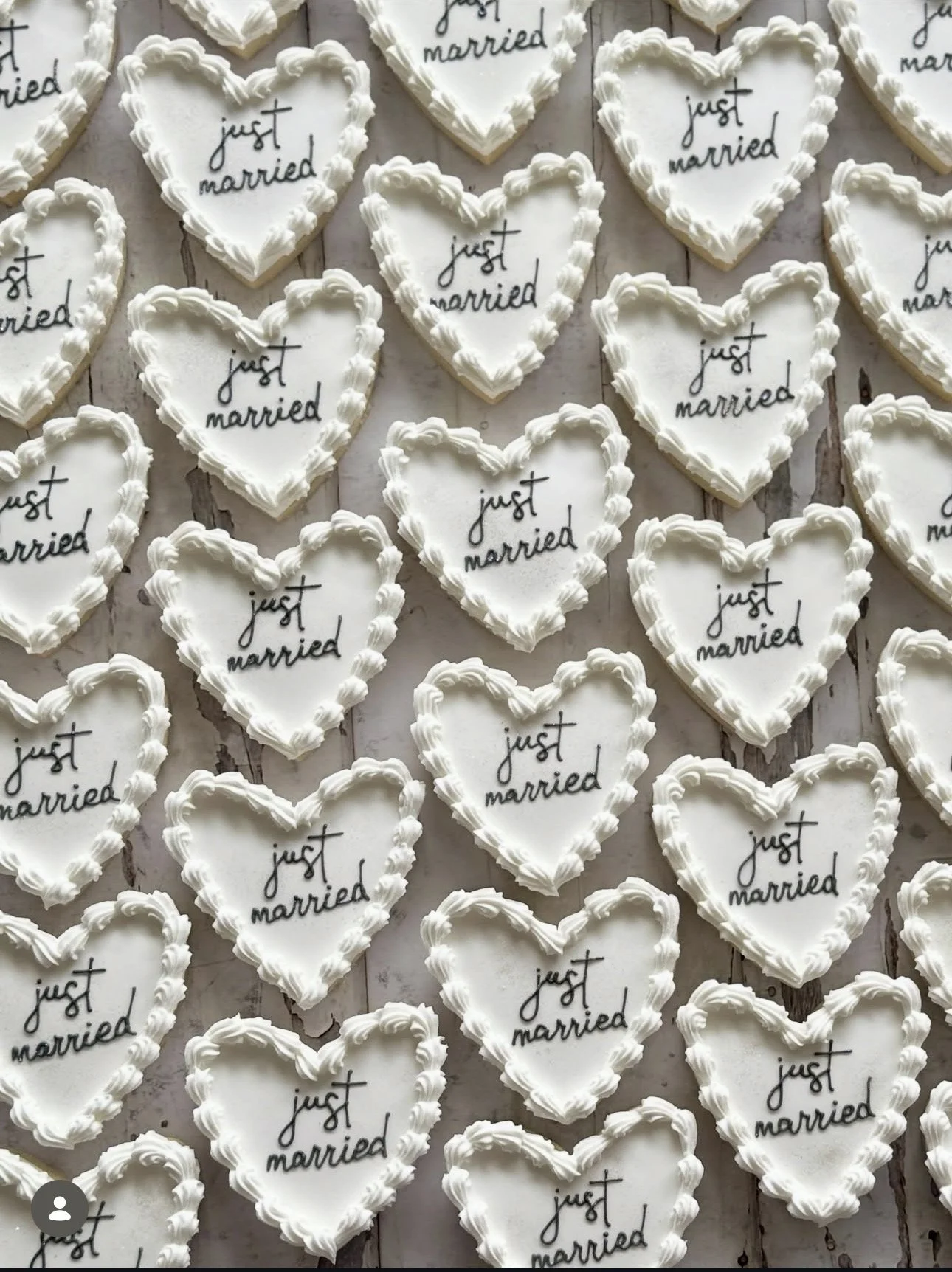 Heart-shaped wedding cookies decorated with white icing and the phrase “just married” on rustic wooden boards
