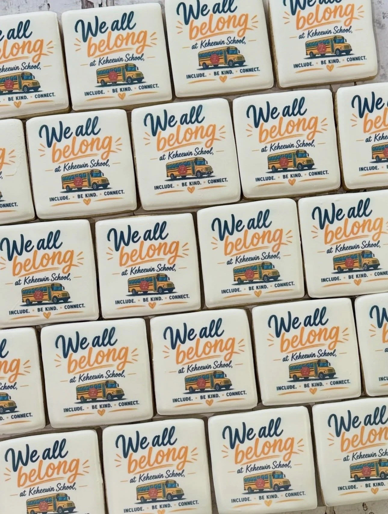 Rows of decorated cookies reading “We all belong at Keheewin School” with school bus illustrations and the words “Include. Be kind. Connect.”