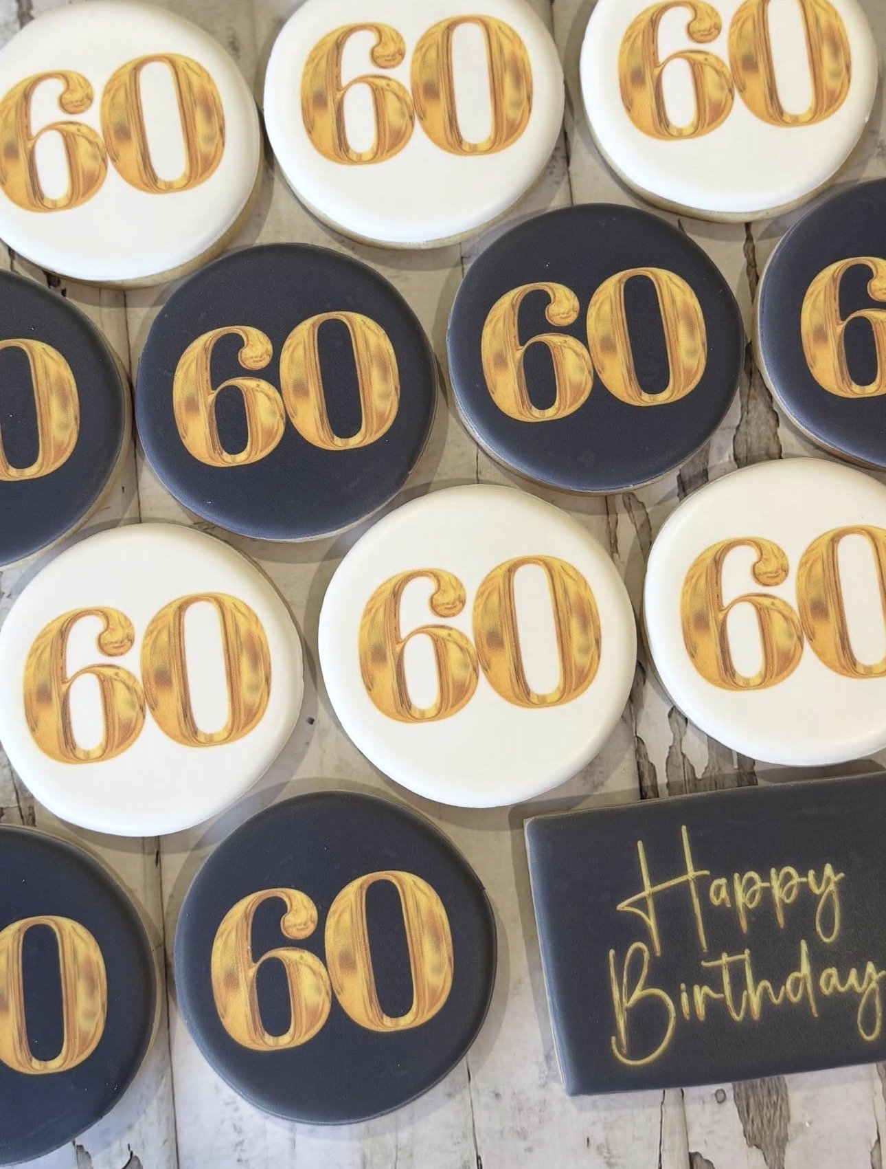 Decorated white and black cookies featuring gold “60” designs alongside a “Happy Birthday” message.