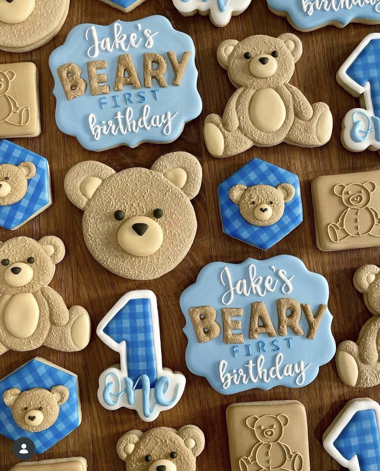 Blue and tan teddy bear-themed cookies for Jake’s first birthday, including bear shapes, blue number one cookies, and decorated birthday message cookies.