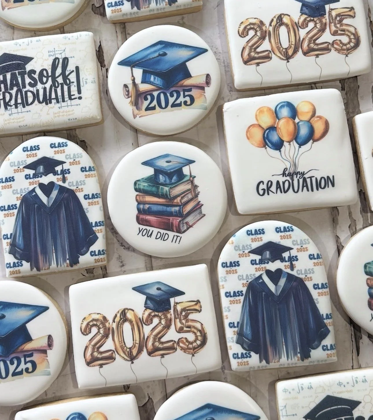 Assortment of 2025 graduation-themed cookies decorated with caps, gowns, diplomas, balloons, books, and congratulatory messages.