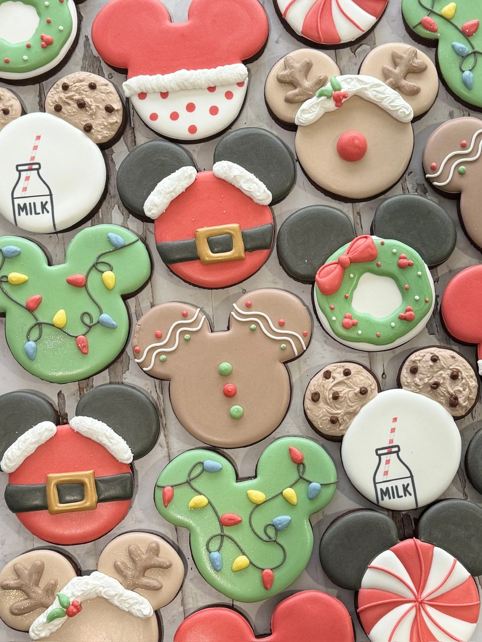 Assorted Christmas-themed iced sugar cookies, including Santa faces, reindeer, gingerbread people, wreaths, Christmas lights, candy canes, milk bottles, and snowflakes.