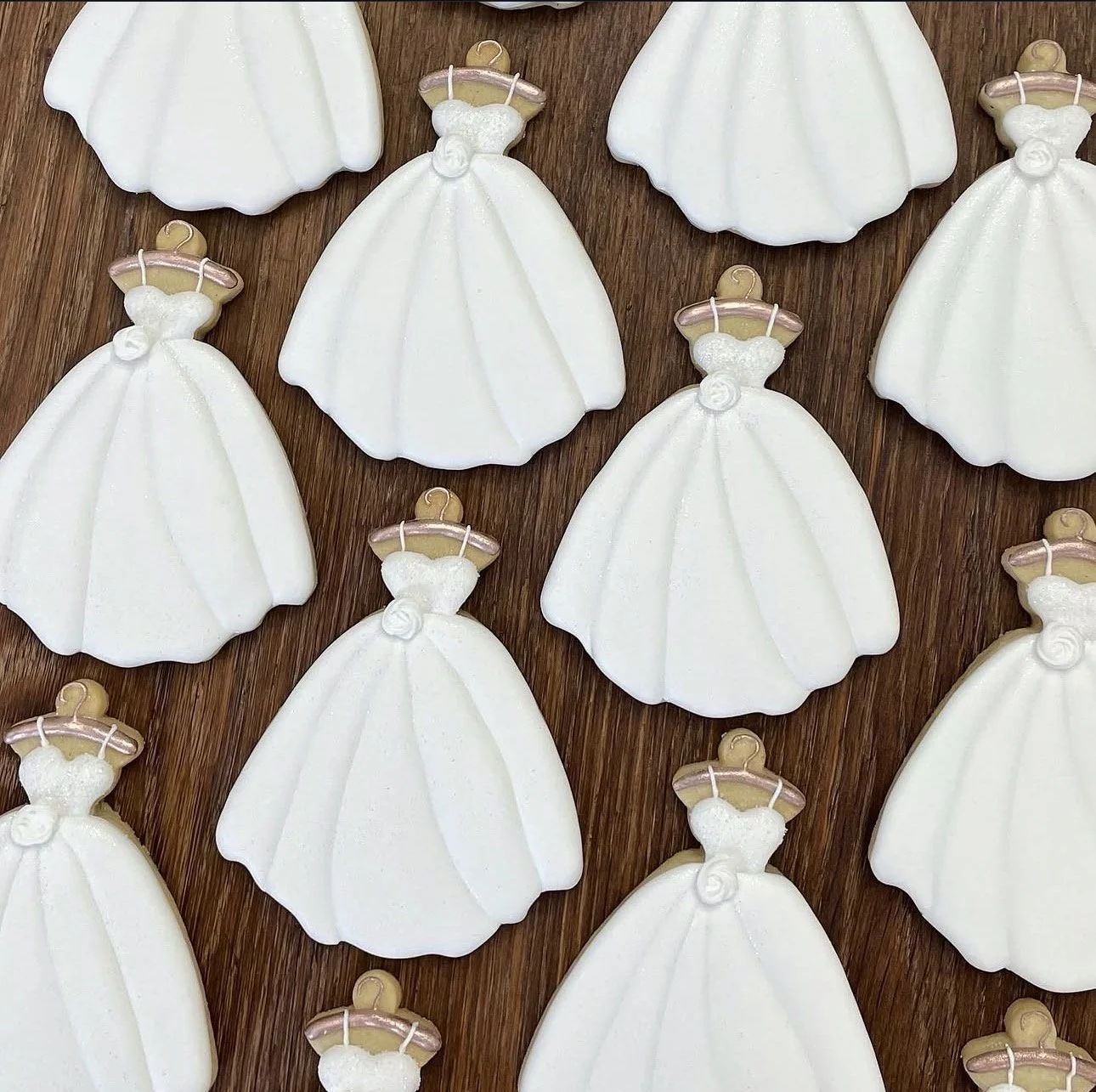 White angel-shaped ornaments with gold and pink halos arranged on a wood-grain background