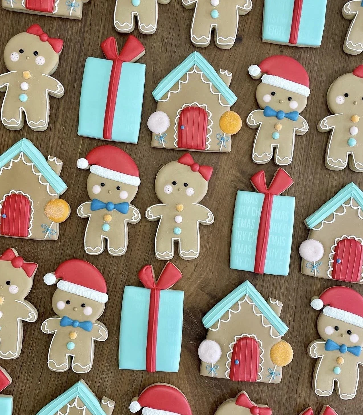 Christmas-themed gingerbread cookies shaped like people, houses, and wrapped gifts on a wooden surface