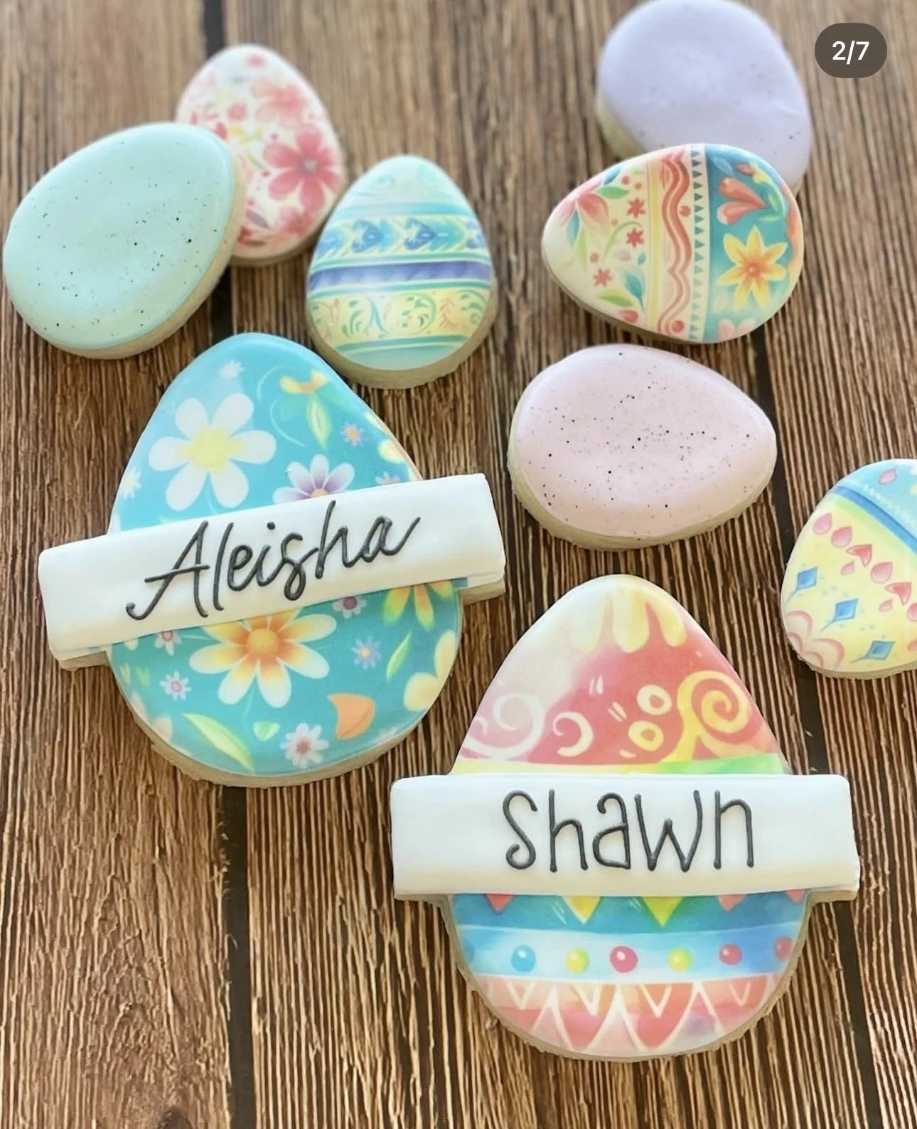 Colorful decorated Easter egg cookies with floral patterns and name tags reading “Aleisha” and “Shawn” on a wooden table