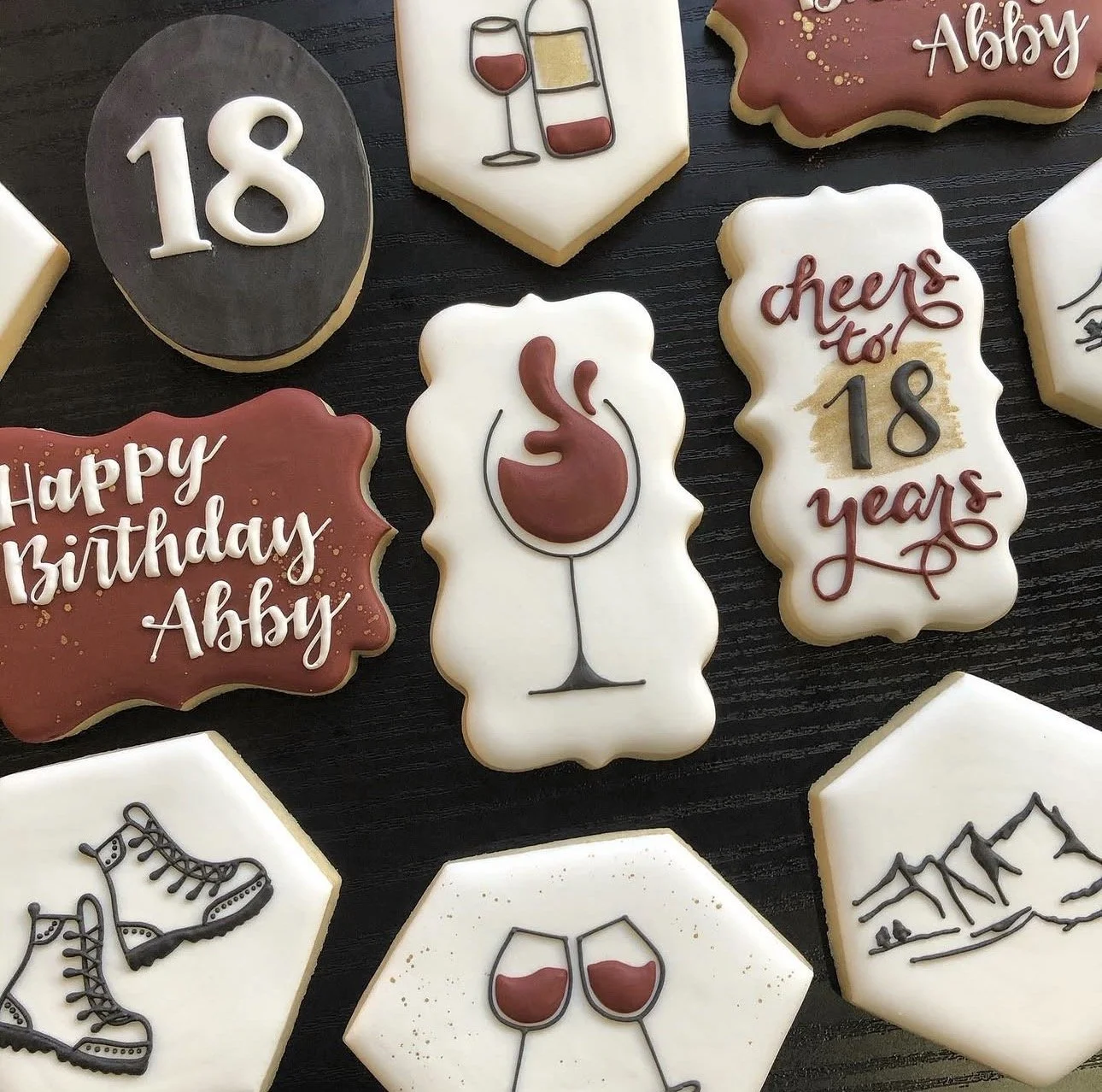 Decorated birthday cookies celebrating Abby’s 18th birthday, featuring wine glasses, a flamingo, ice skates, mountains, and birthday messages.