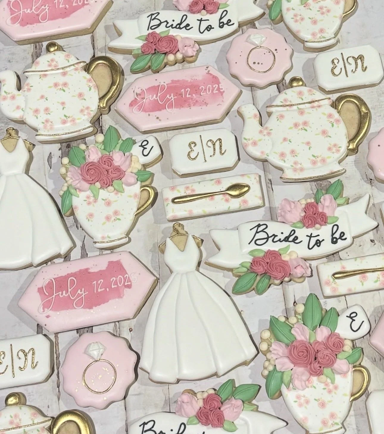 Decorated bridal shower cookies with floral teapots, pink roses, wedding rings, a bridal gown, and “Bride to Be” and “July 12, 2025” lettering