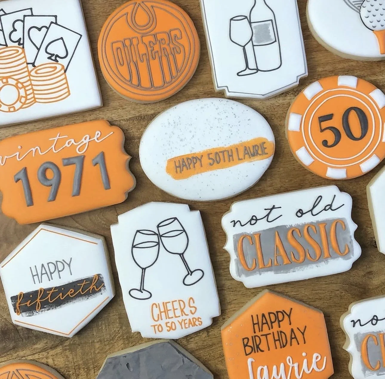 Assorted vintage-themed 50th birthday cookies on a wooden table, including poker chips, wine glasses, and messages celebrating 50 years.