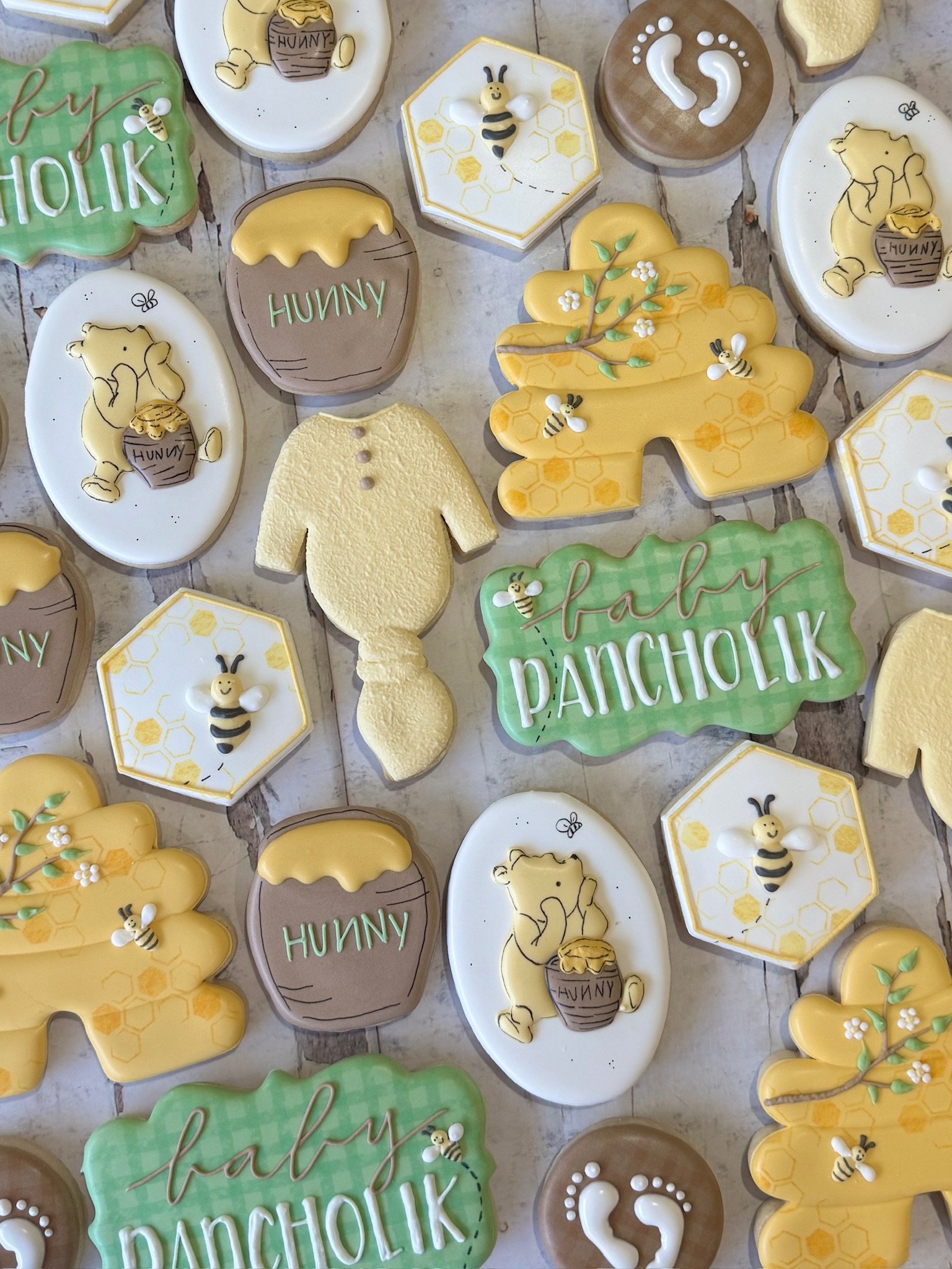 Assorted Winnie-the-Pooh and honey-themed decorated sugar cookies, including bees, honey jars, honeycomb patterns, and woodland shapes.