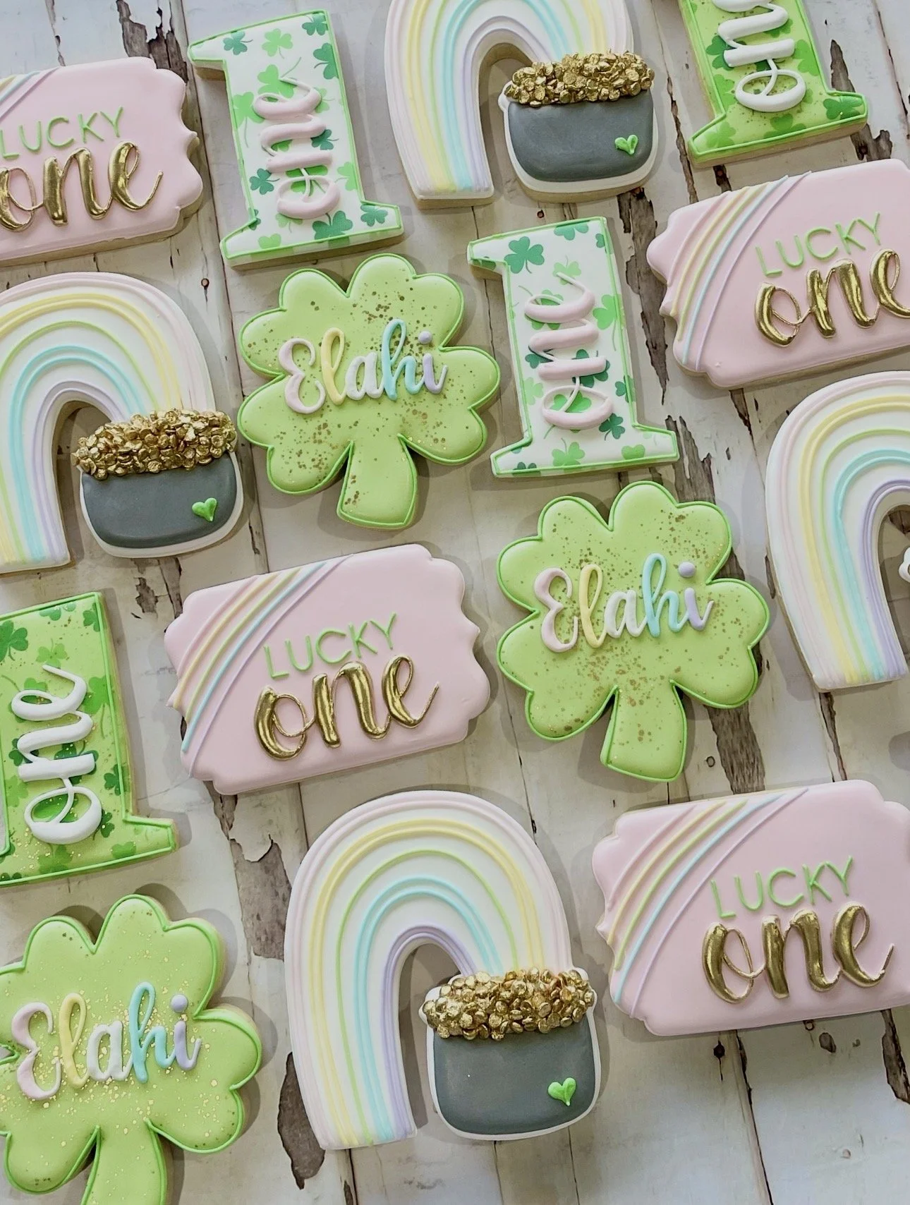 Decorated St. Patrick’s Day sugar cookies featuring rainbows, four-leaf clovers, shamrocks, gold pots, and the words “Lucky” and “Elahi.”