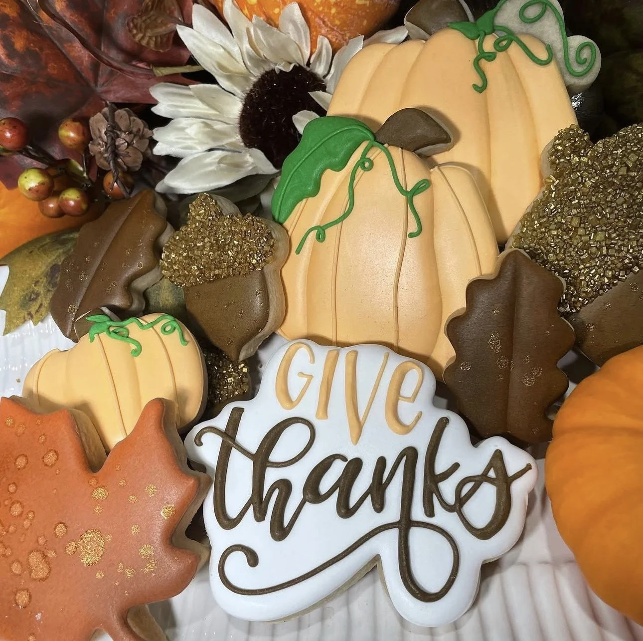 Autumn-themed decorated cookies featuring pumpkins, acorns, leaves, sunflowers, and a cookie reading “Give Thanks.”