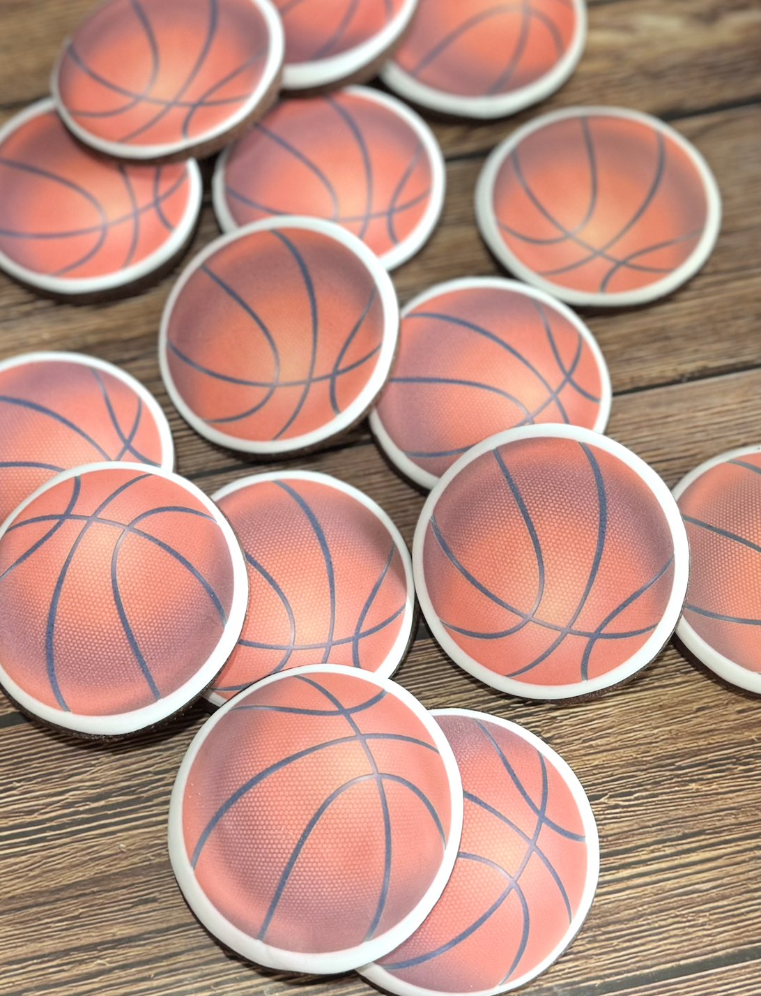 Multiple basketball-themed round cookies scattered on a wooden tabletop