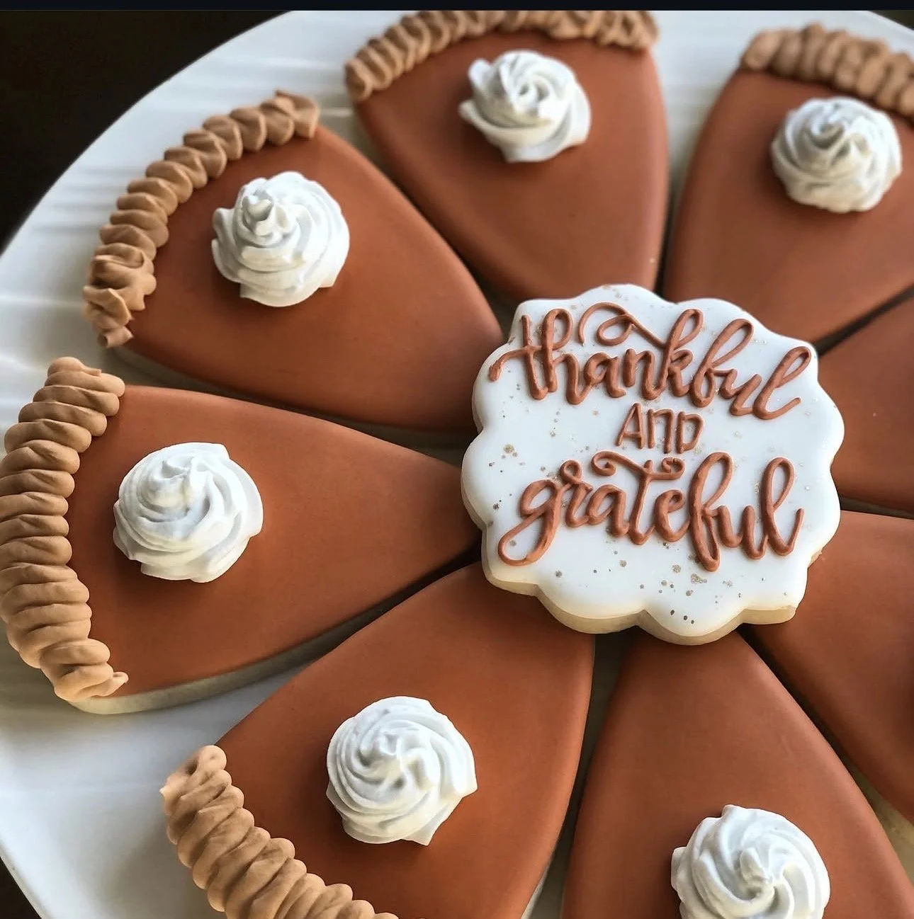 Pumpkin-shaped decorated cookies with white frosting and a “Thankful and Grateful” message