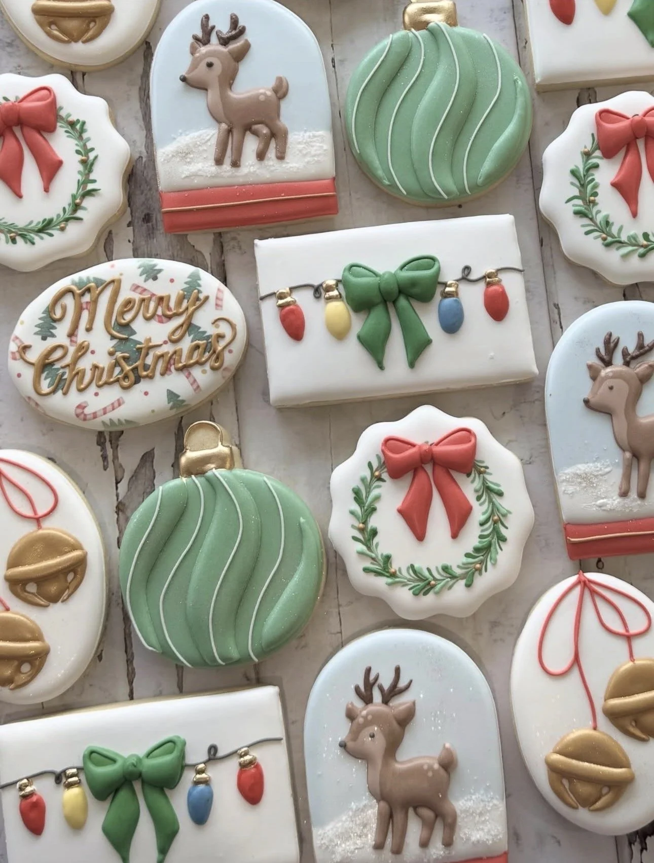Assorted Christmas cookies decorated with reindeer, wreaths, bows, ornaments, string lights, bells, and “Merry Christmas” lettering