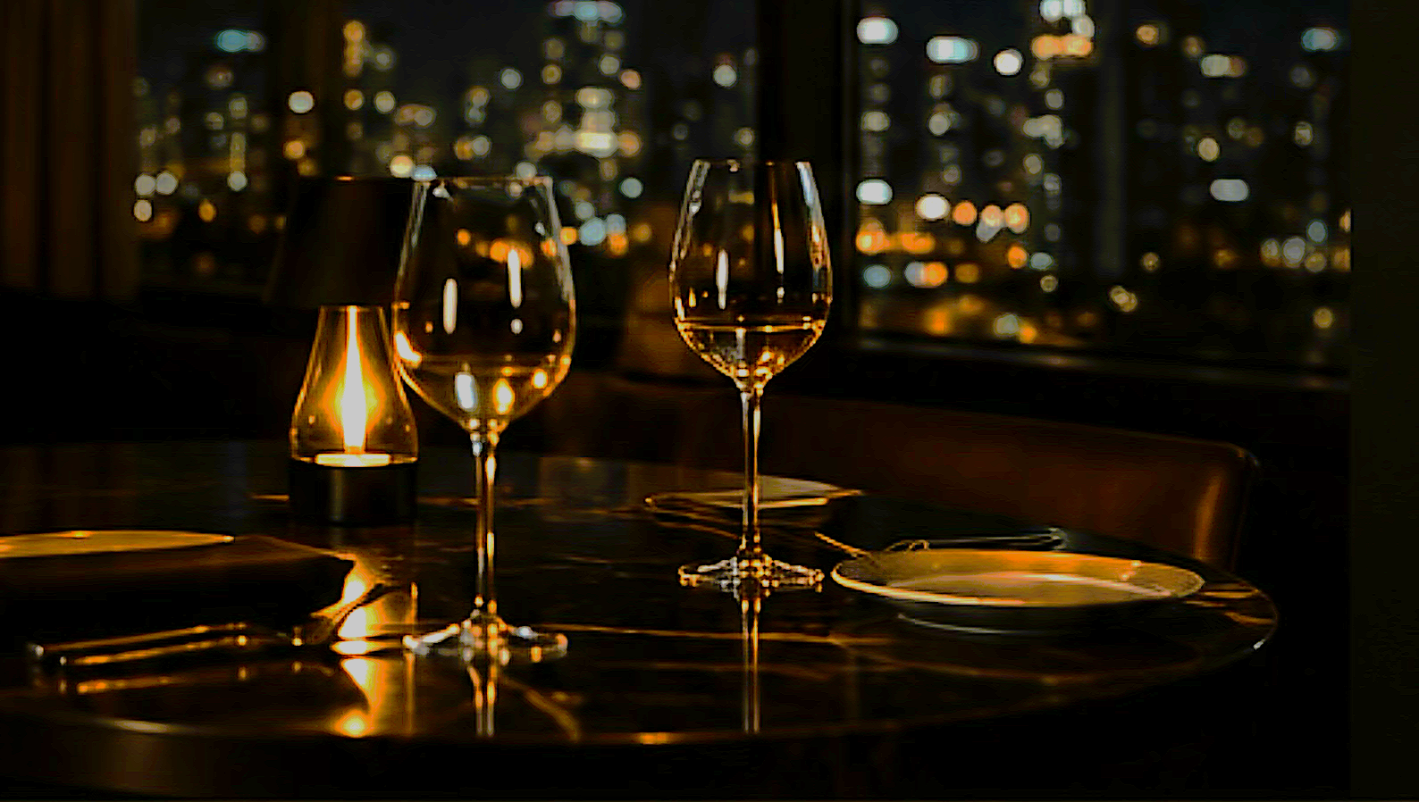 James Hart. An elegant dining table at night with two wine glasses, a candle, Melbourne