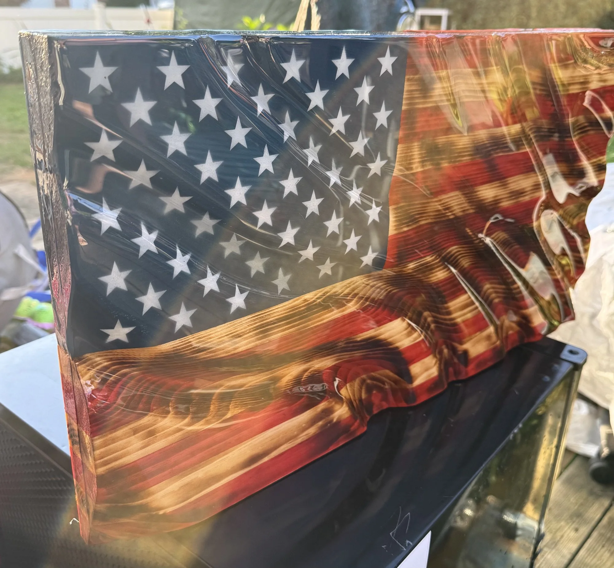Close-up of a wrapped package with an American flag design, featuring white stars on a dark blue field and red and yellow stripes, sitting outdoors.