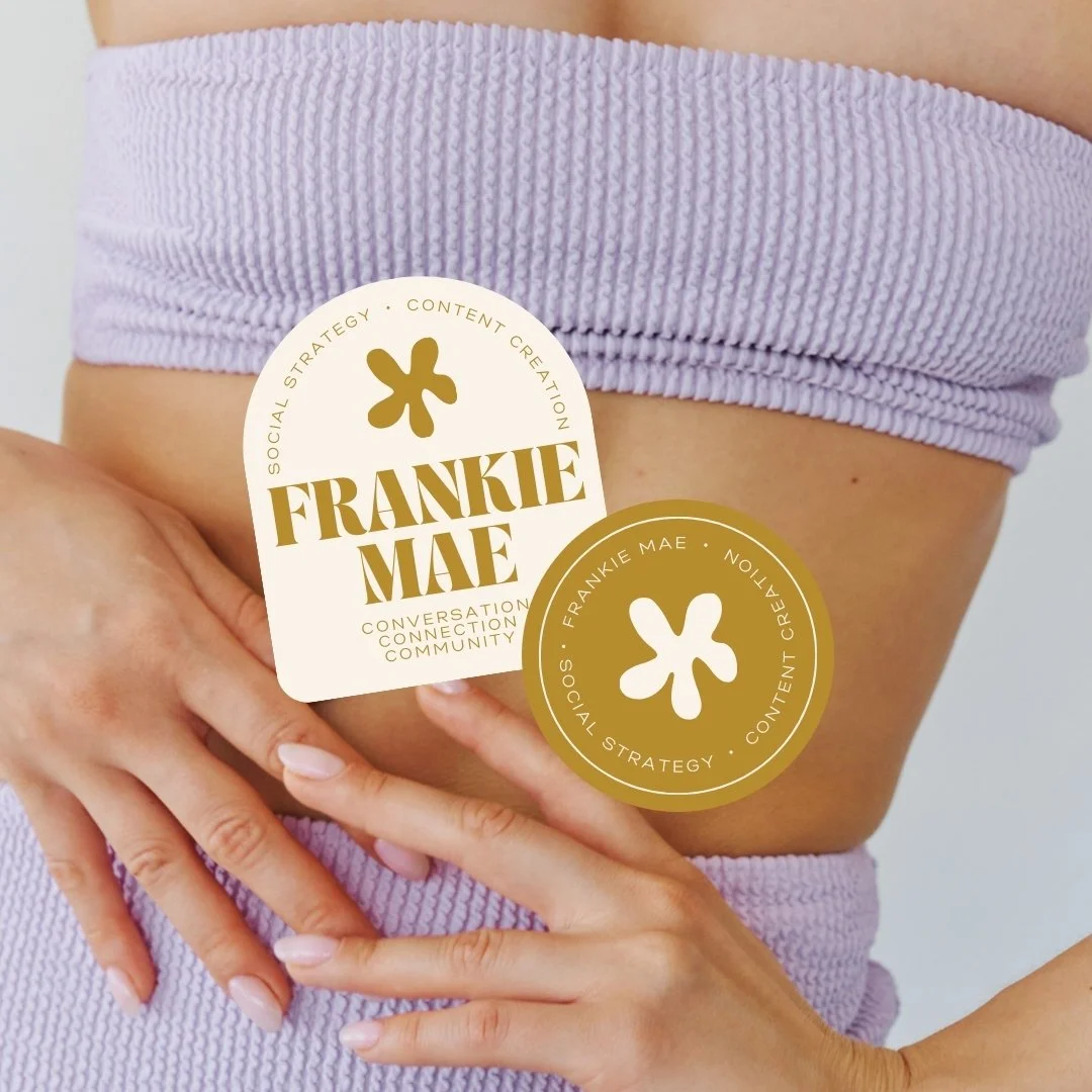 Close-up of a woman wearing lavender clothing with two circular stickers on her torso. The stickers display the name "Frankie Mae" with text "Social Strategy" and "Content Creation" surrounding a stylized flower logo.