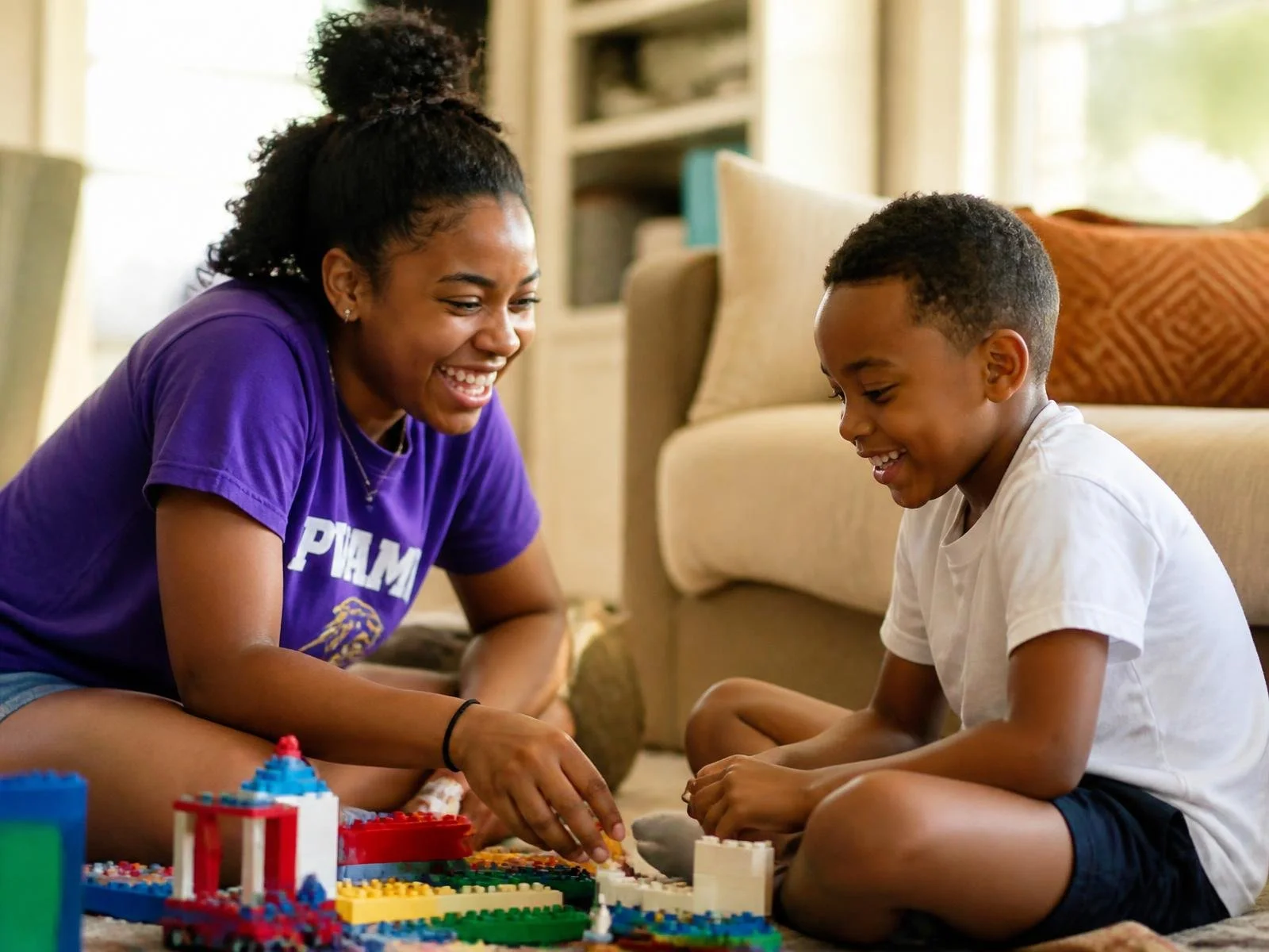 Athlete caregiver laughing with a child while building LEGO at home