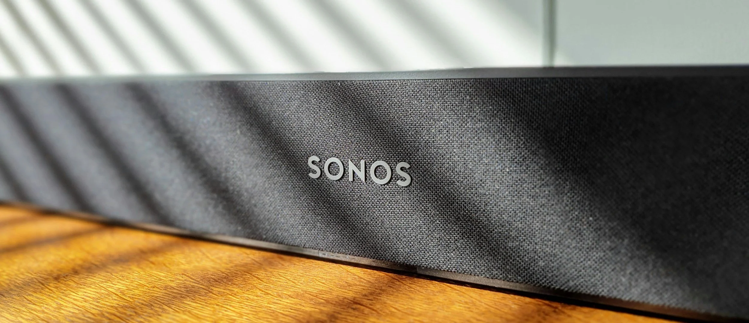 Close-up of a black SONOS speaker on a wooden surface.